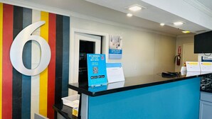 Ein Empfangsbereich mit einer großen Zahl 6 an der Wand, einer blauen Theke und Hinweisschildern zu Mitgliedschaftspreisen sowie Informationen zum Thema Menschenhandel.