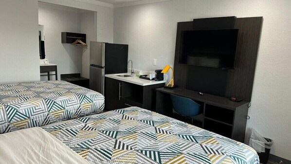 A hotel room with two beds, a desk with a chair, a TV, and a small kitchenette. - Studio 6 Suites San Ysidro, CA -San Diego South Bay (San Ysidro)