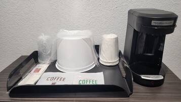 Une machine à café, une cafetière blanche et un plateau avec un paquet de café sur une table en bois.