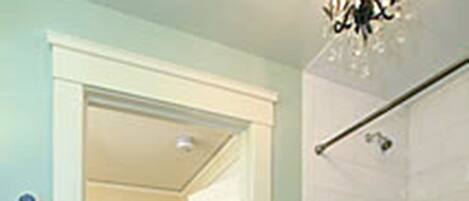 A bathroom with a bathtub, a shower, and a toilet. There is a door leading to another room.
