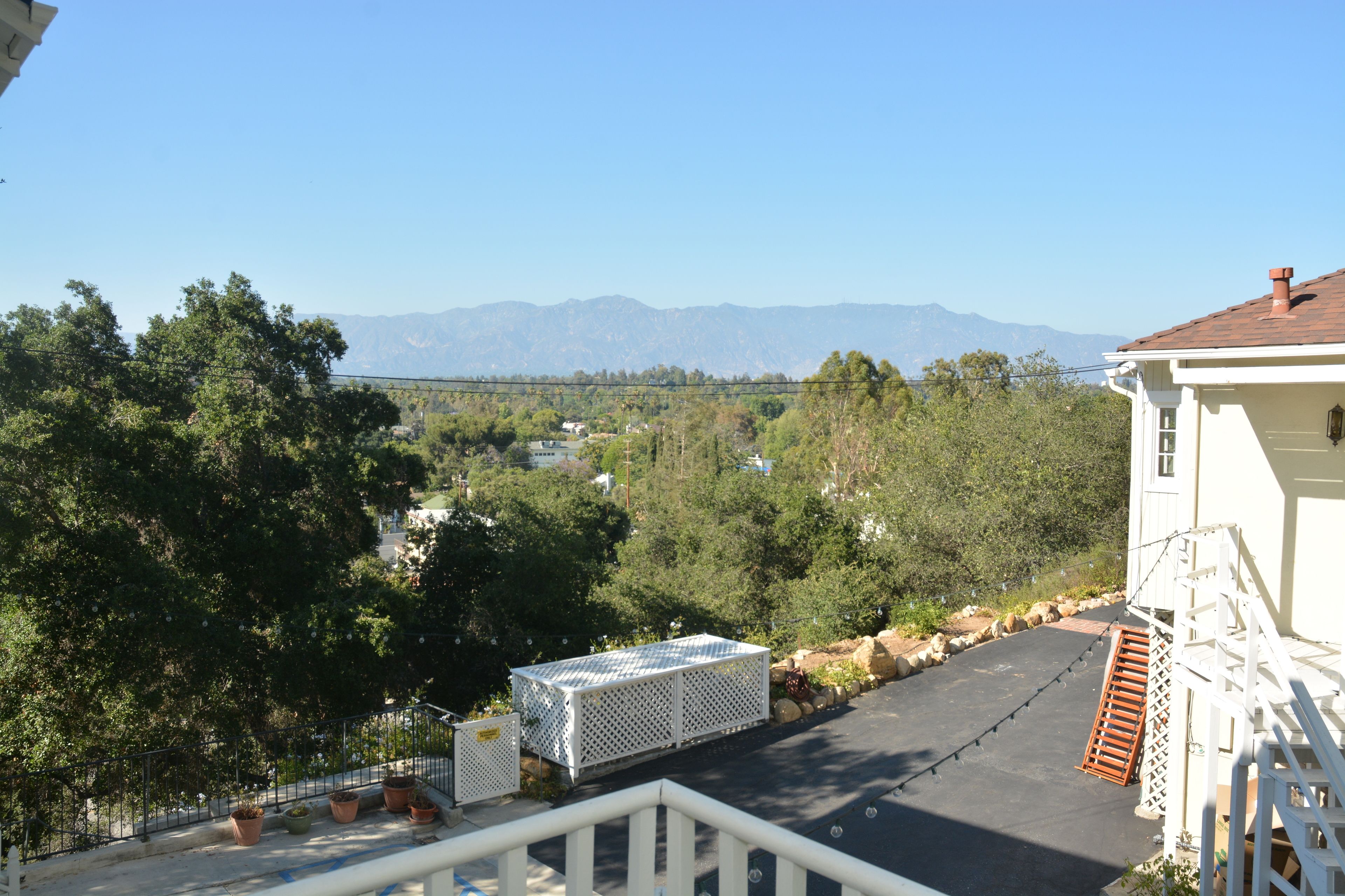 A residential area with a view of mountains, a paved driveway, and a white building with a red roof.