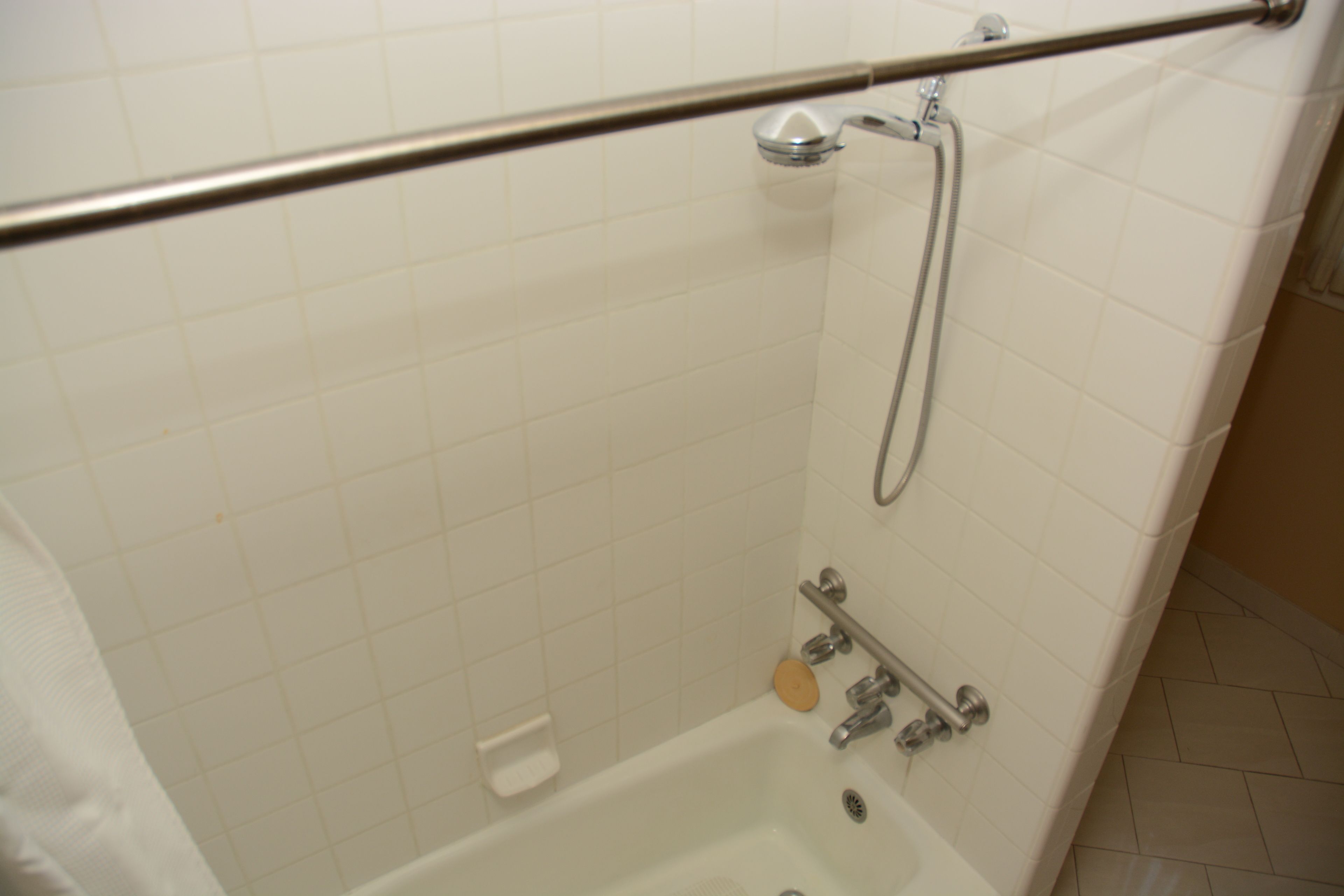 Un baño con bañera, ducha y barra de apoyo.