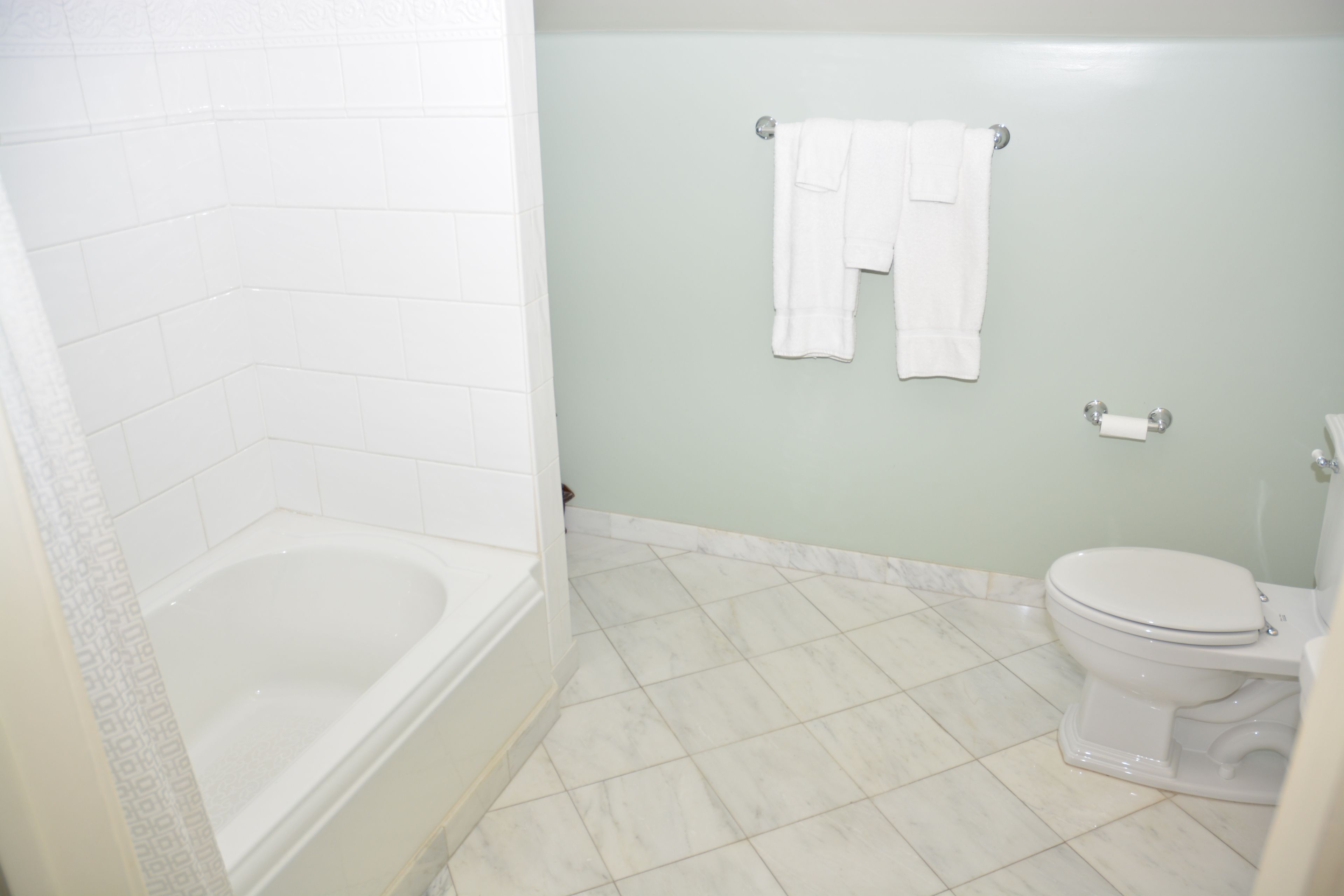 A bathroom with a bathtub, toilet, and a towel rack.
