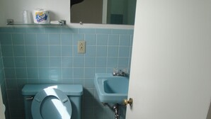 A bathroom with a toilet, sink, and blue tiles. - Budget Motel (Grand Island)