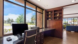 Une chambre d’hôtel équipée d’un bureau, d’un ordinateur et d’une grande fenêtre donnant sur la rue.