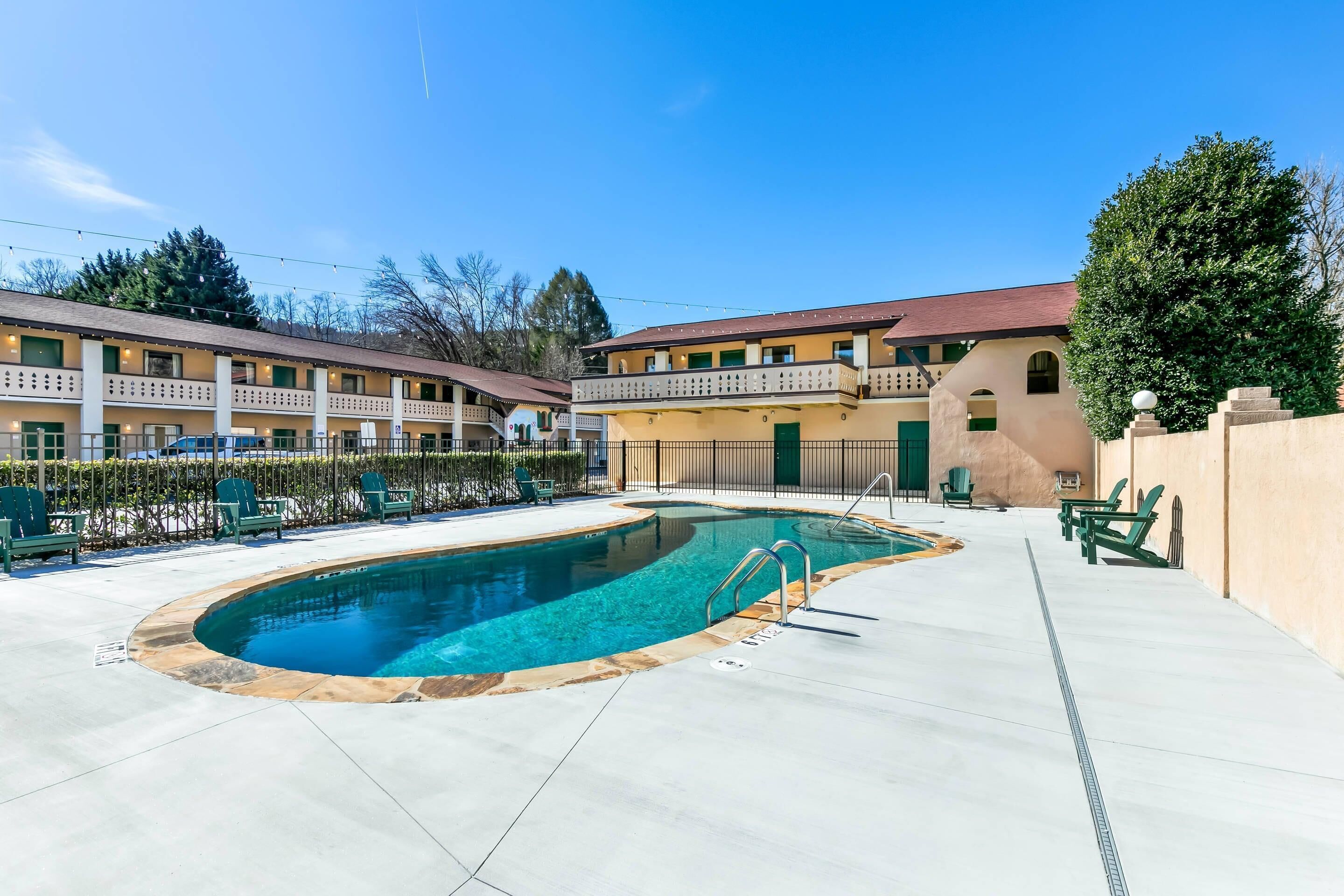 Un hôtel doté d’une piscine, d’un espace extérieur aménagé et surplombant un ciel d’un bleu limpide.