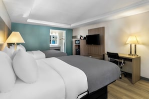 A hotel room with two beds, a desk, a chair, a TV, and a mirror.