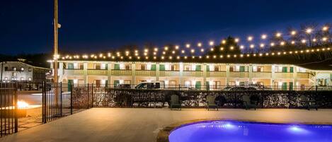 Un hotel con piscina, zona de estar exterior y fachada bien iluminada.