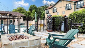 A patio area with Adirondack chairs, a stone fire pit, and a bear statue. - Quality Inn Downtown Helen (Helen)