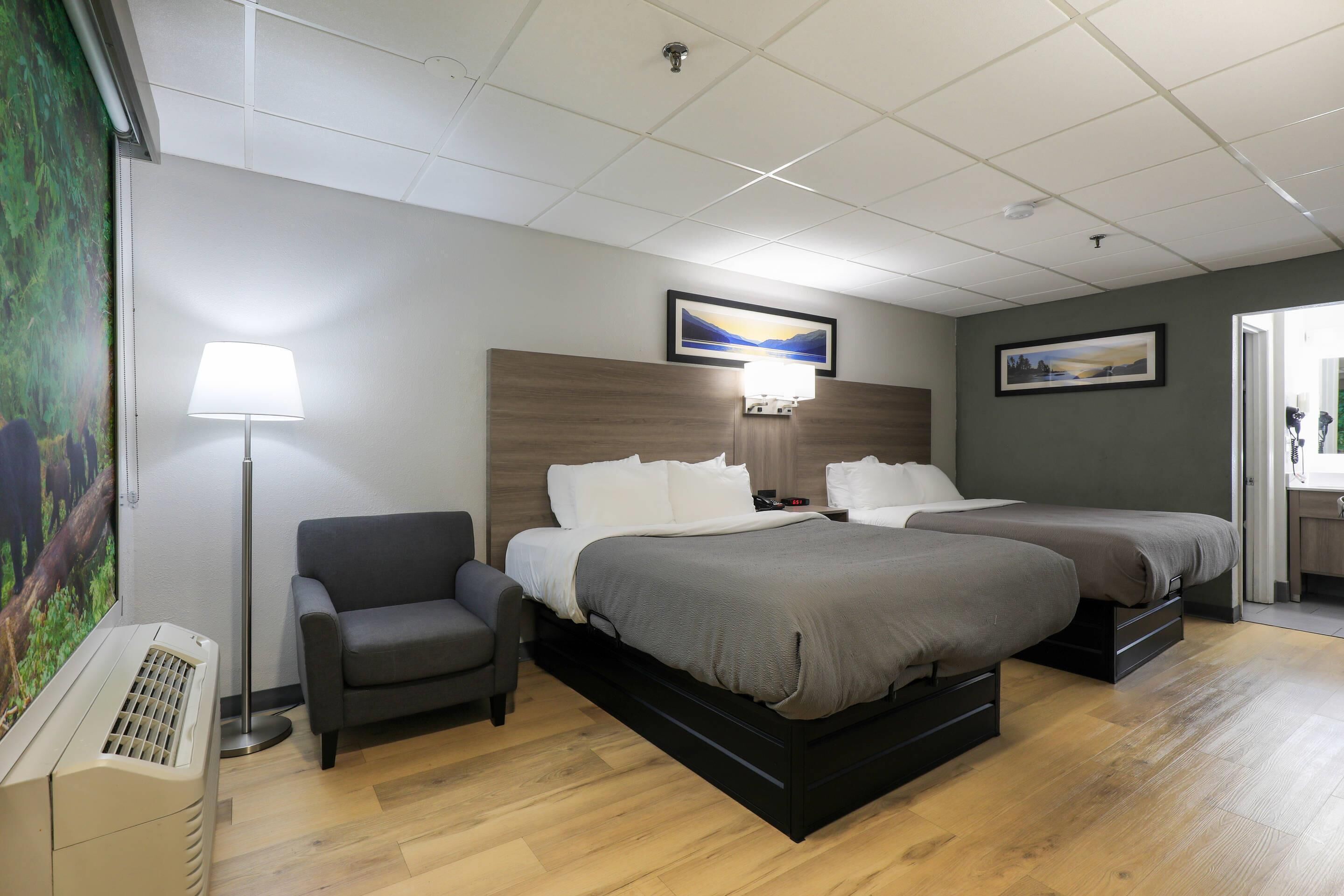 Une chambre d’hôtel avec deux lits, un canapé, une télévision et un tableau au mur.