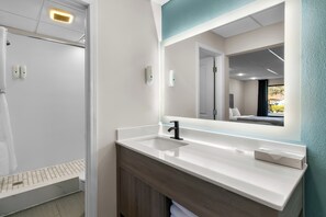 A modern bathroom with a white sink, a large mirror, and a shower area. - Quality Inn Downtown Helen (Helen)