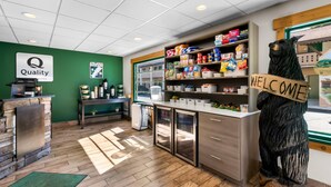 A coffee shop interior with a reception desk, coffee machines, and a welcome sign on a bear statue. - Quality Inn Downtown Helen (Helen)