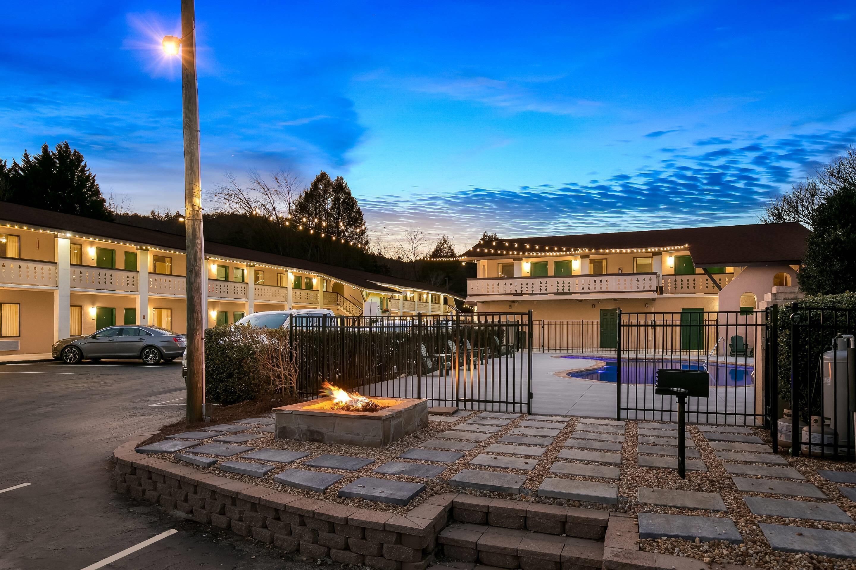 A hotel courtyard with a swimming pool, a fire pit, and a car parked outside.