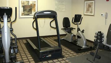 Un gimnasio con cintas de correr, elípticas y equipo de pesas.