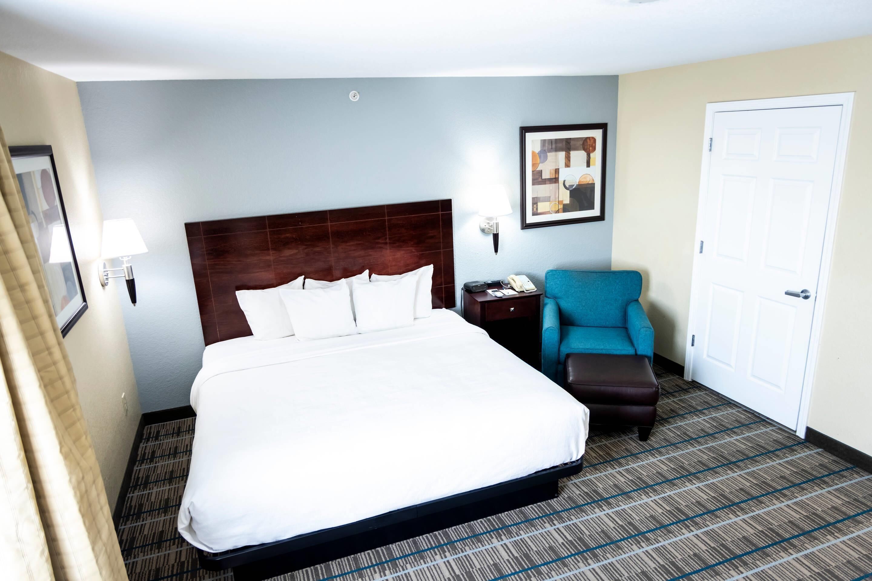 Una habitación de hotel con una cama grande, un escritorio con lámpara, una silla y una puerta.