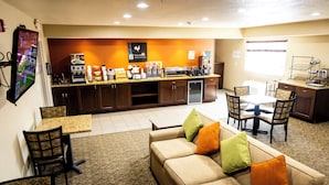 Un hall de hotel con un área de descanso, kitchenette y estación de café.