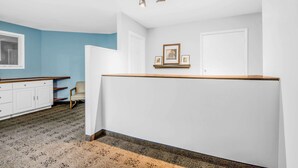 A room with a white wall, a blue accent wall, a wooden bench, a white cabinet, and a framed picture on the wall. - Knights Inn Pine Grove (Pine Grove)
