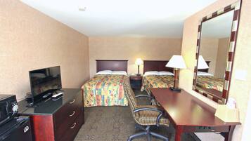 A hotel room with two beds, a desk, a chair, a television, and a mirror.