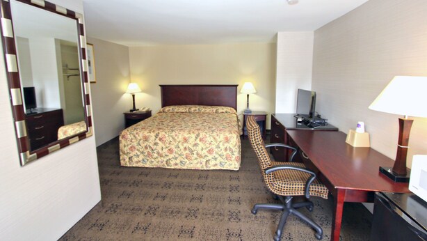 A hotel room with a bed, desk, chair, lamps, and a TV. - Knights Inn Pine Grove (Pine Grove)