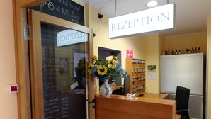 A reception area with a wooden desk, a sign reading "RECEPTION", and a chalkboard menu listing prices. - PrivatHotel Probst (Nuremberg)