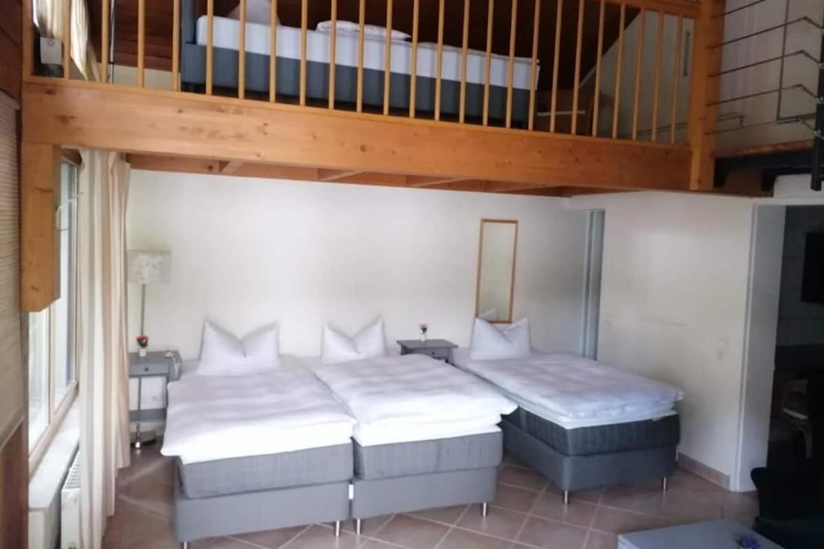 Een slaapkamer met twee bedden, een houten plafond en een raam met gordijnen.