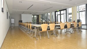 A conference room with long tables and chairs, large windows, and a whiteboard.
