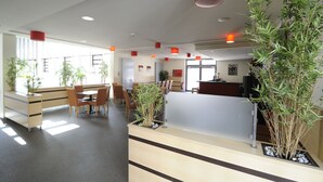 A modern reception area with a reception desk, seating area, and potted plants.