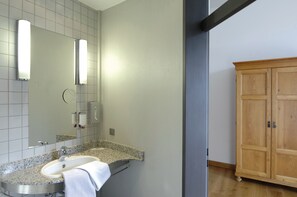 A bathroom with a granite countertop sink, a mirror, and a wooden cabinet. - Hotel MutterHaus Düsseldorf (Düsseldorf)