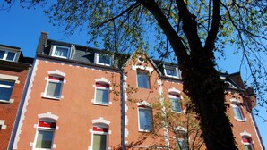 A red brick building with multiple windows and a tree in front. - Hotel Rheinischer Hof (Düsseldorf)