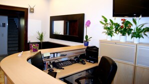 A modern office with a curved desk, computer, printer, and a large mirror. There are potted plants and a flat-screen TV on the wall. - Hotel Rheinischer Hof (Düsseldorf)