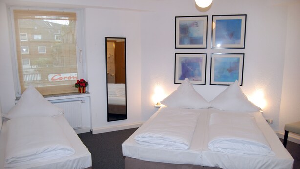 A hotel room with two beds, a window with a view, a mirror, and framed pictures on the wall. - Hotel Rheinischer Hof (Düsseldorf)