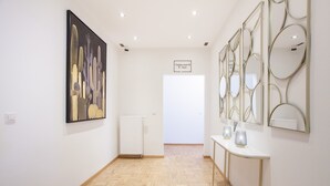 A hallway with a wooden floor, a white wall, and a framed artwork depicting cacti. - TM Hotel Düsseldorf (Düsseldorf)