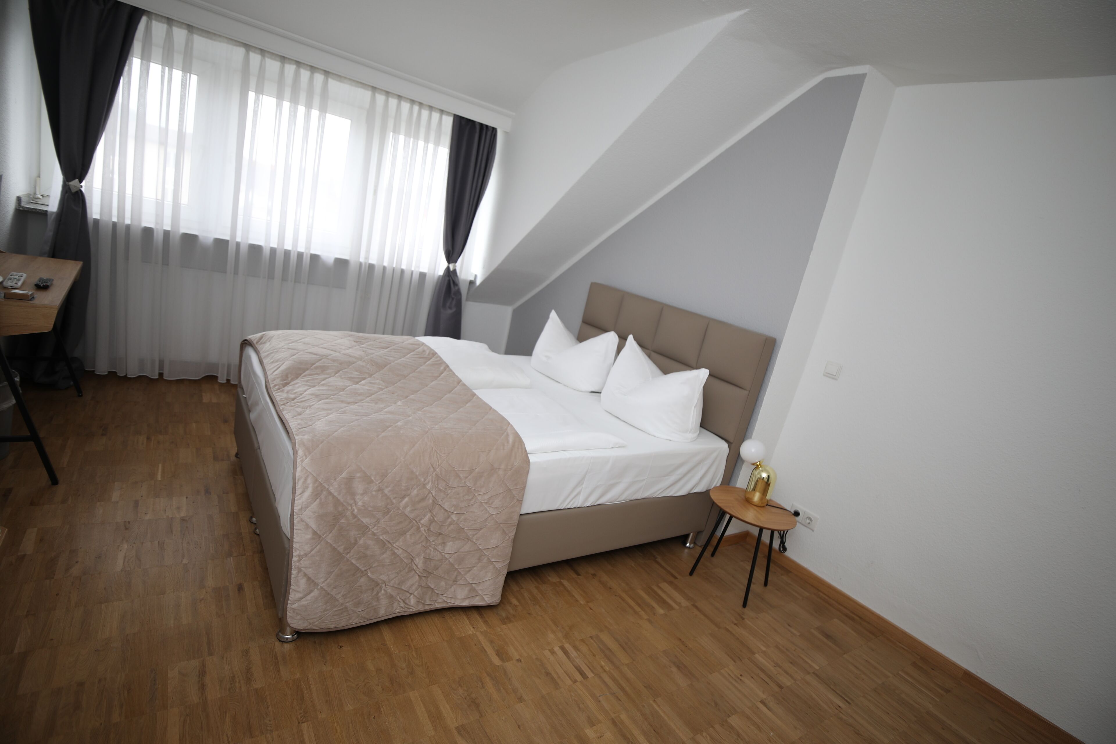 Een slaapkamer met een groot bed, een bureau en een raam met gordijnen.