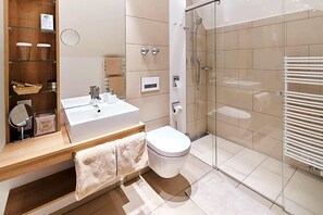Un bagno moderno con box doccia in vetro, lavandino bianco e water.