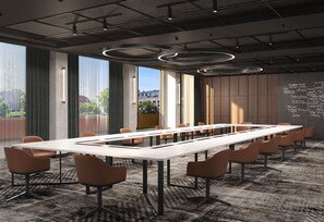 Un salón de conferencias con una larga mesa, sillas y vistas amplias a través de grandes ventanales.