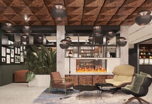 Un espacio lounge moderno con chimenea, asientos y una planta grande.