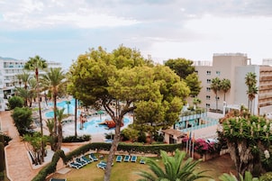 Un resort con piscina, palmeras y vistas de los edificios circundantes.
