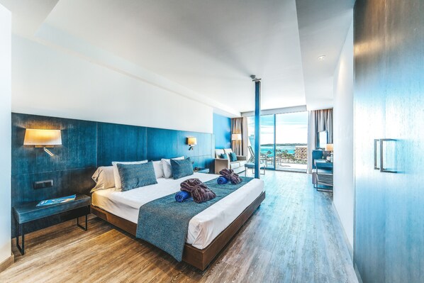 A modern hotel room with a large bed, a bench, and a view of the outdoors. - Marins Playa (Son Servera)