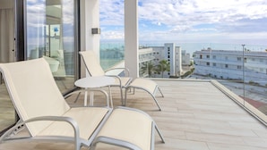 A balcony with two chairs and a small table, overlooking a cityscape and the sea. - Marins Playa (Son Servera)