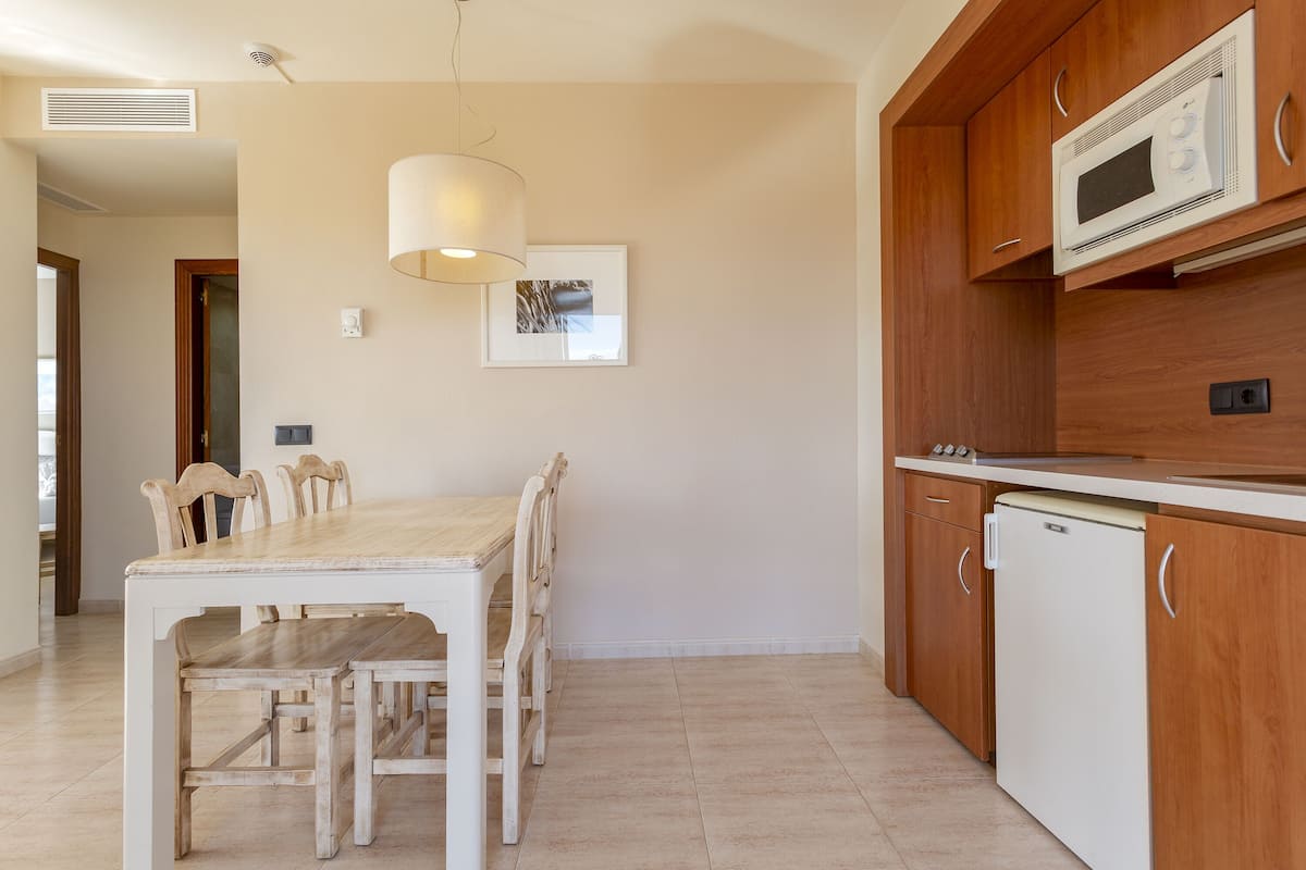 Una cocina con una mesa de madera, sillas, microondas y refrigerador.