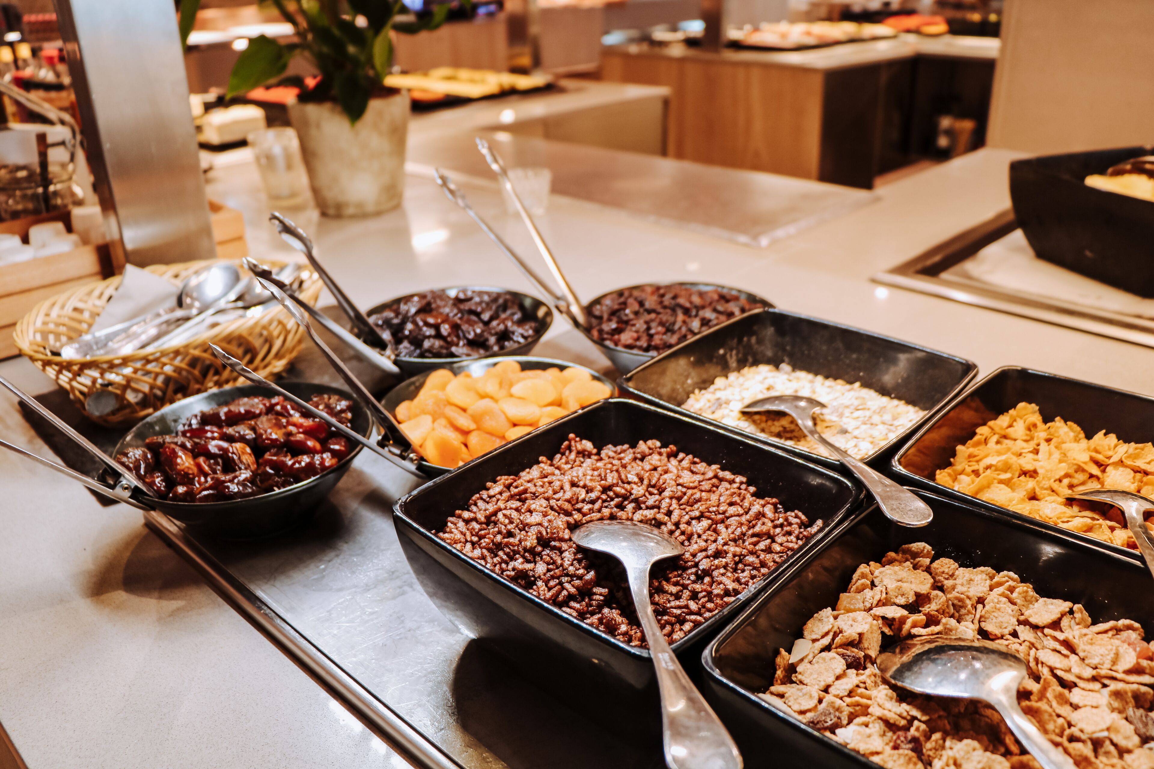 En buffet med et udvalg af madvarer, herunder frugt, nødder og morgenmadsprodukter.
