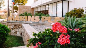 A sign for "MARINS PLAY" with a stone wall and greenery in the foreground. - Marins Playa (Son Servera)