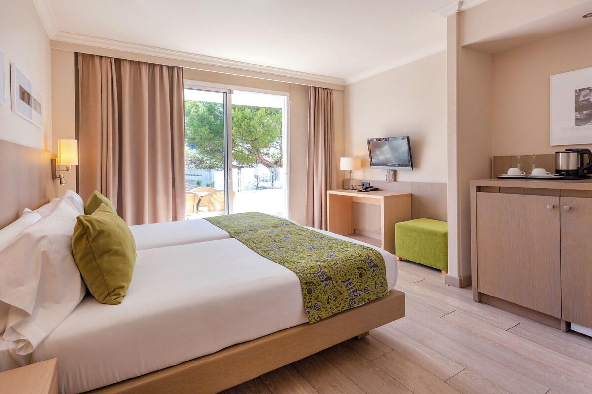 Een hotelkamer met een bed, bureau, televisie en kitchenette.
