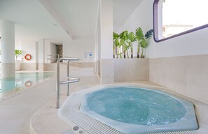 A hot tub area with a pool, a lifebuoy, and potted plants.