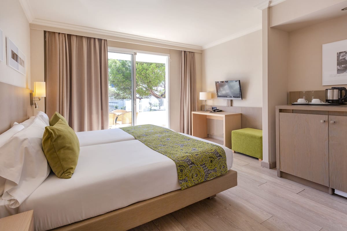 Una habitación de hotel con cama, escritorio, televisor y kitchenette.