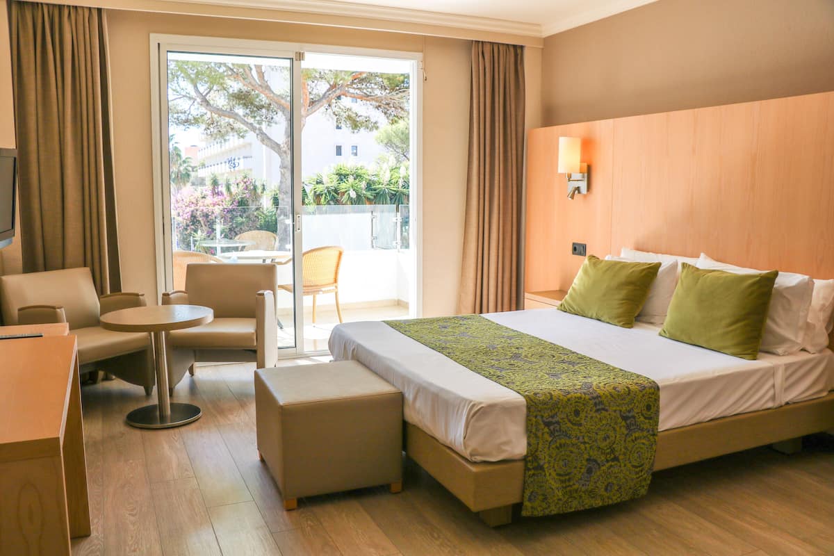 Una habitación de hotel con cama, sofá, mesita y silla.
