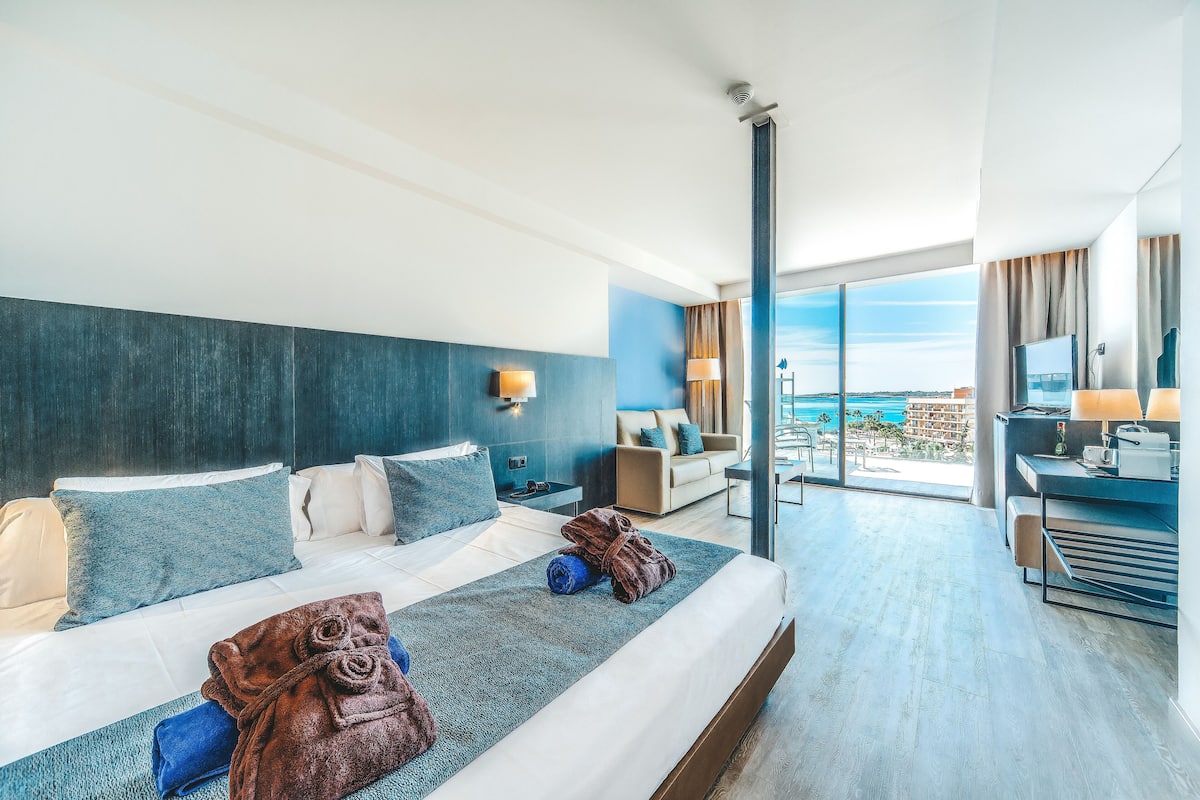 Habitación de hotel moderna con una cama grande, un escritorio y vistas a la ciudad.