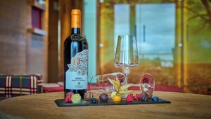 A bottle of wine, a glass, and assorted fruits on a table.