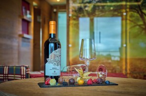 A bottle of wine, a glass, and assorted fruits on a table.
