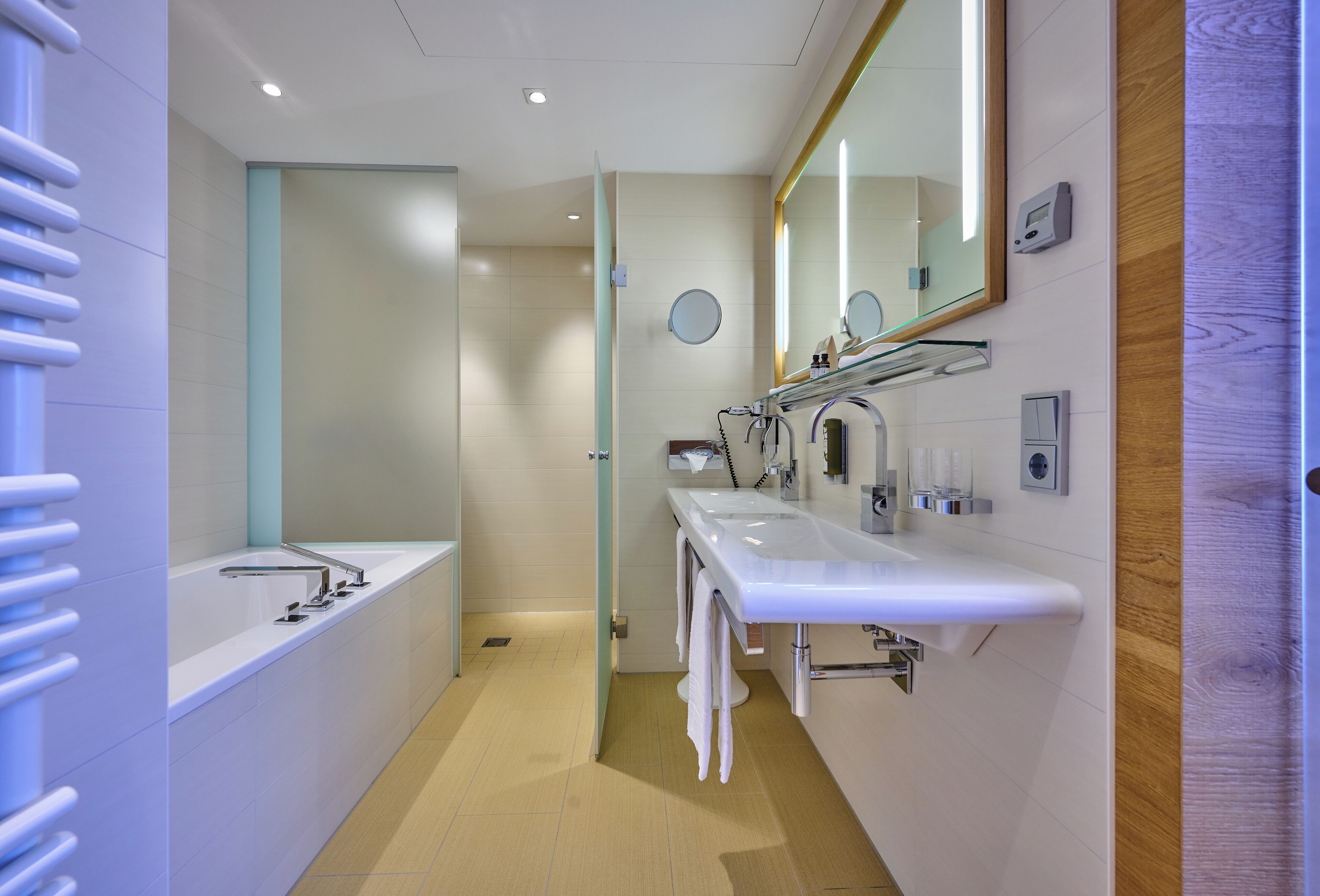 A modern bathroom with two sinks, a large mirror, and a towel rack.